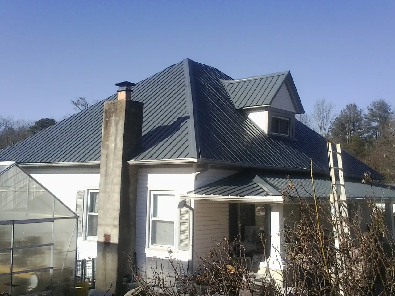 Dark blue standing seam metal roof on a white farmhouse with dormer — Slate & Tile Roof Repair by Roofing Brothers in Topton