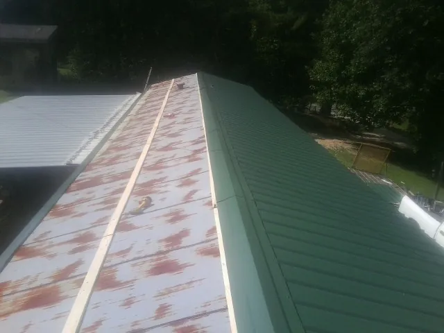 Old rusted panels beside newly installed green metal roofing — Wind Damage Roof Repair by Roofing Brothers in Topton