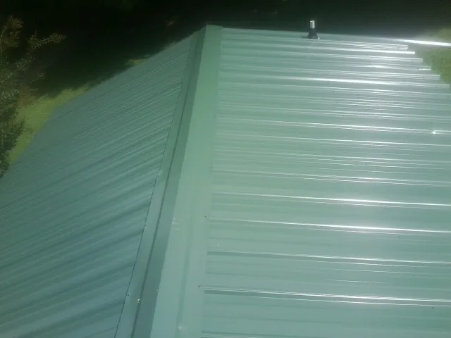 New green metal panels meeting at the ridge of a roof — Flat Roof Repair work by our crew in Topton