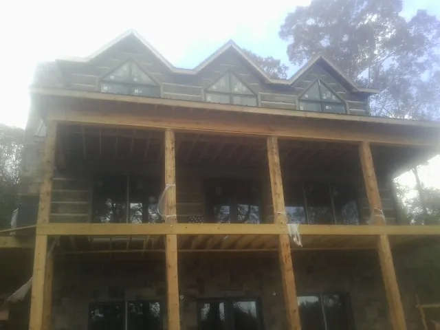 Dormers and porch framing on a large log home under construction — Roof Coating work by our crew in Topton