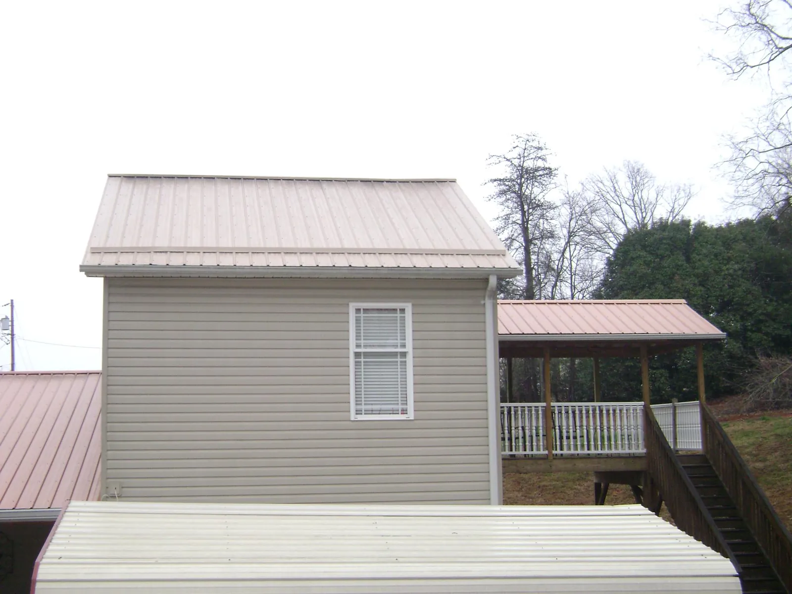 Tan metal roofs on a two story addition and attached porch, from a Roof Replacement job in Topton