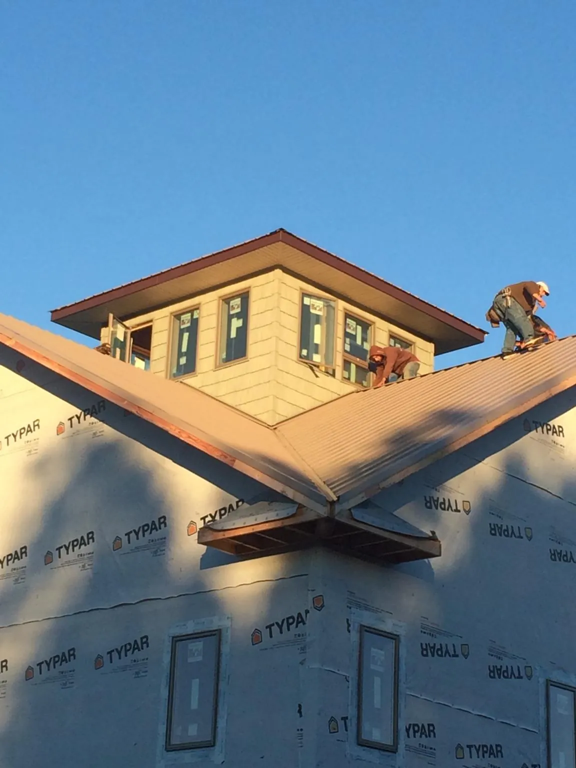 Roofers working around a rooftop cupola on a new metal roof at sunset — Roof Waterproofing in Topton by Roofing Brothers